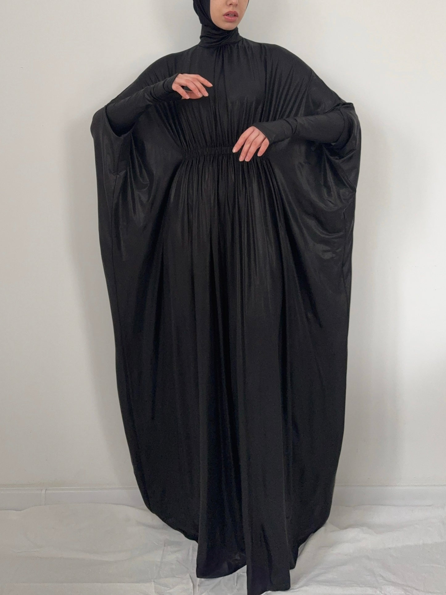 Black abaya worn by a person on a white background