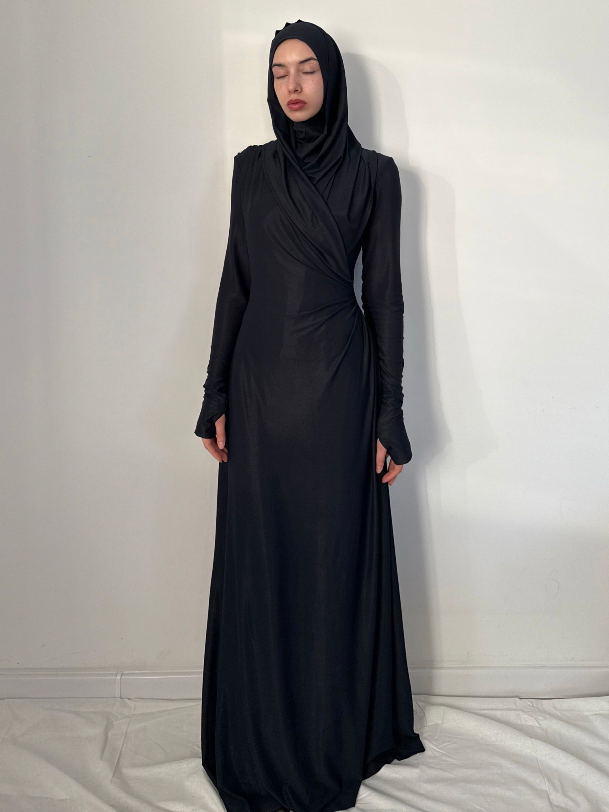 Person wearing a black abaya against a white background