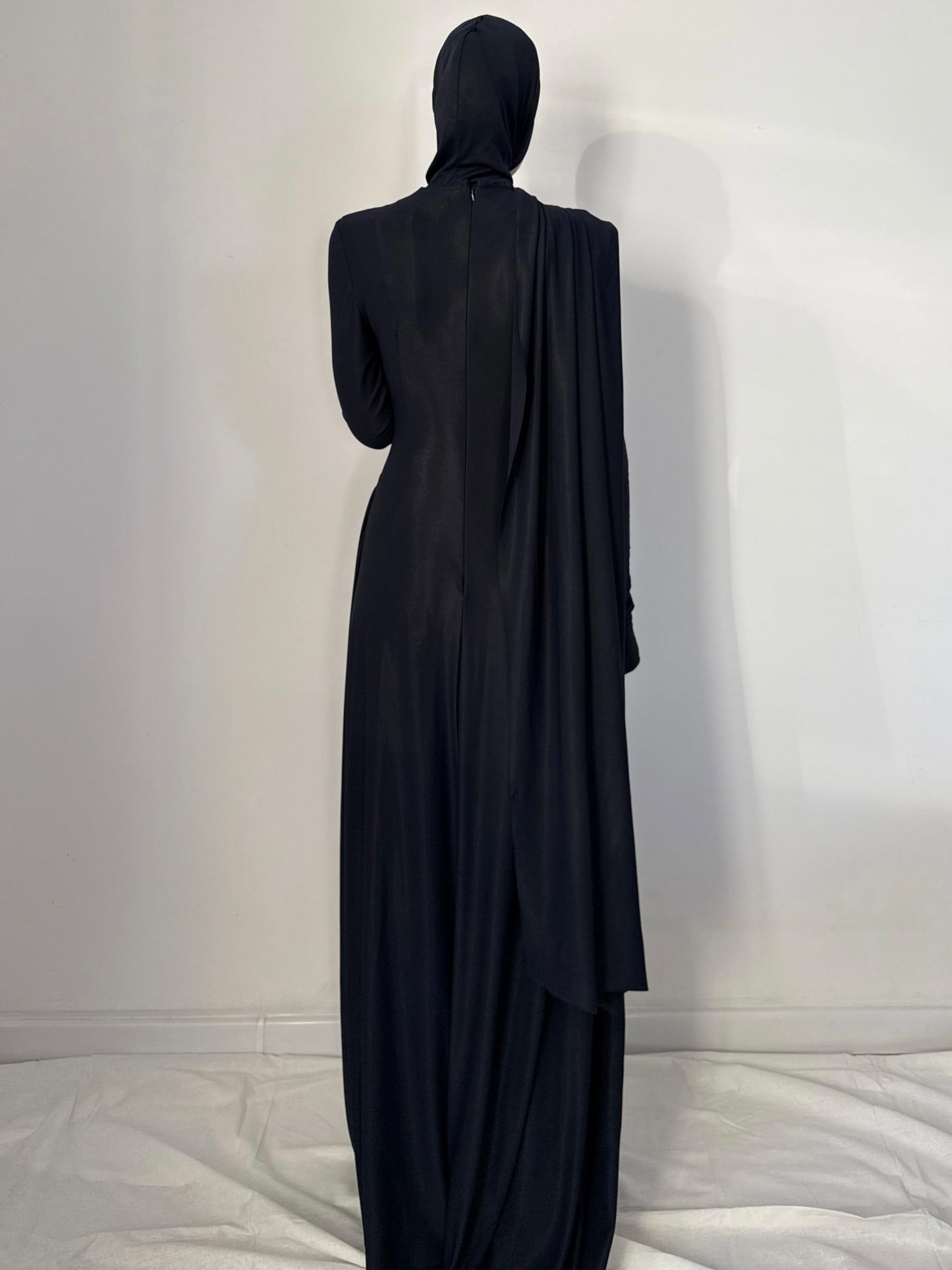 Black abaya worn by a person against a white background