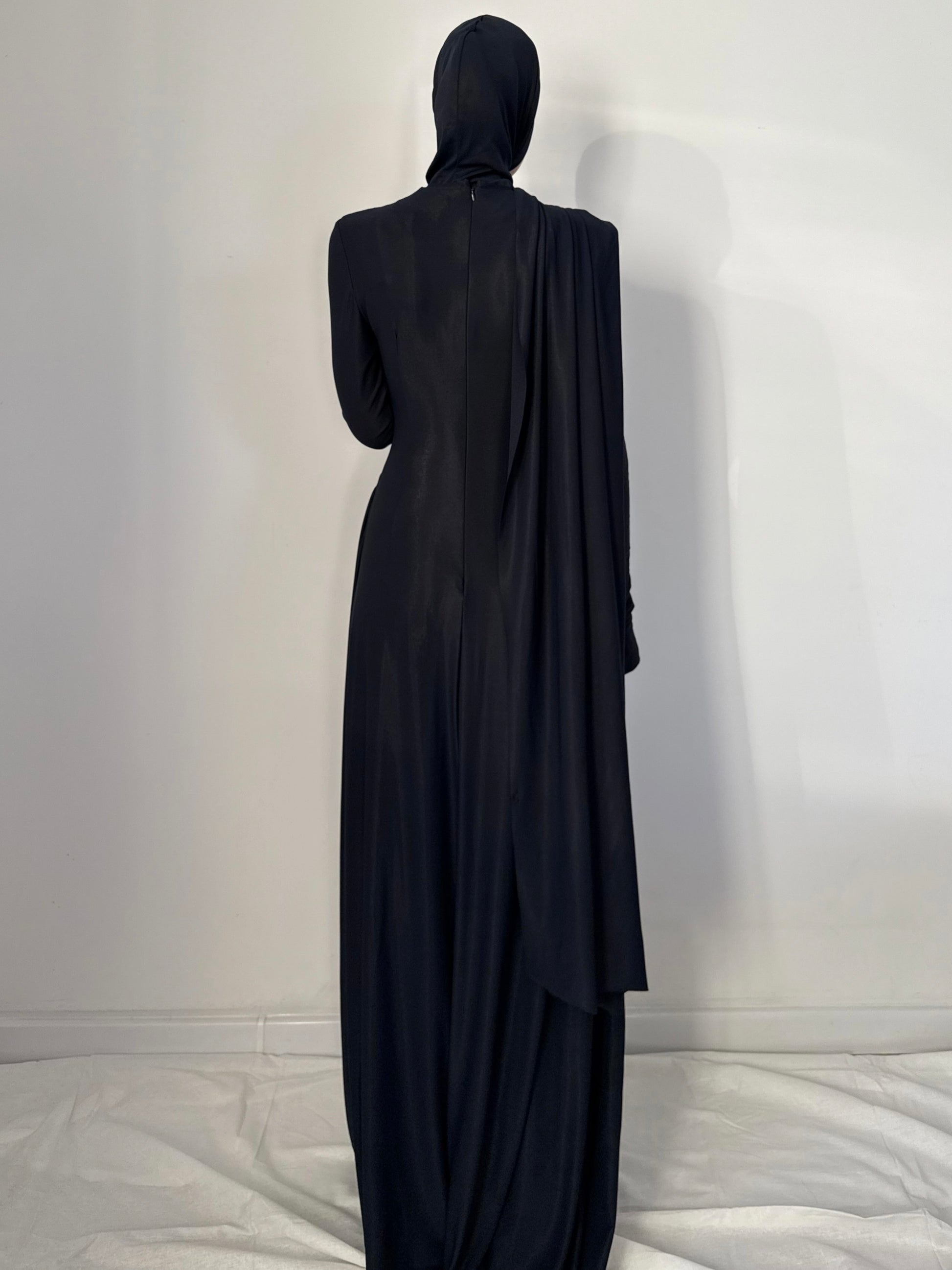 Black abaya worn by a person against a white background
