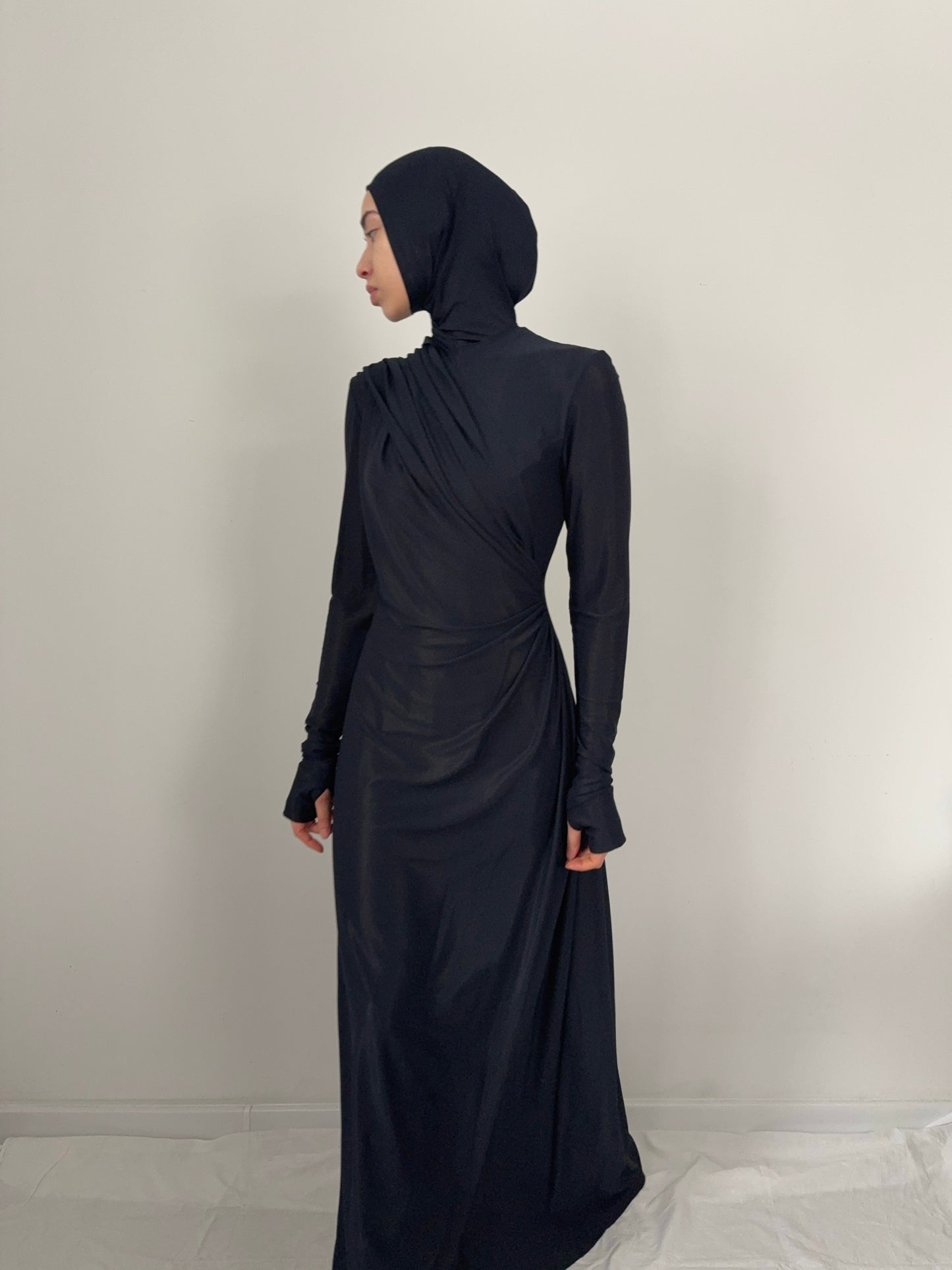 Person wearing a black abaya and hijab against a plain background